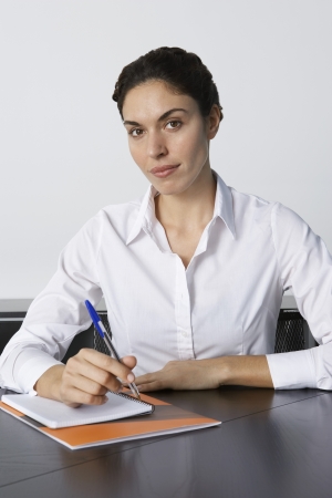 Business woman writing at desk in office portraitの写真素材