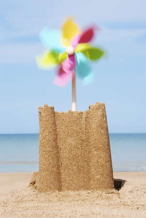 Sand castle with moving pinwheel on beach close-upの写真素材