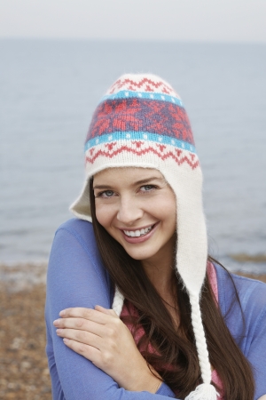Young woman wearing wool hat on beach portraitの写真素材