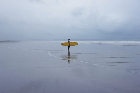 Lone surfer standing in shallow water side viewの写真素材
