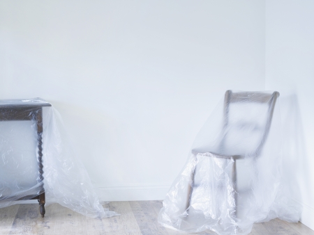 Chair and table covered by plastic in empty roomの写真素材
