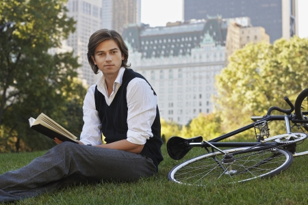 Man sitting on lawn holding book portraitの写真素材