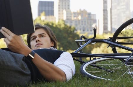 Man lying on lawn reading book close-upの写真素材