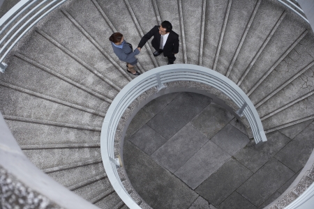 China Hong Kong two business people shaking hands standing on spiral staircase view from aboveの写真素材