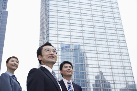 China Hong Kong three business people standing amongst skyscrapers low angle viewの写真素材