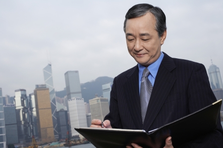 Middle-aged business man with documents office building in backgroundの写真素材