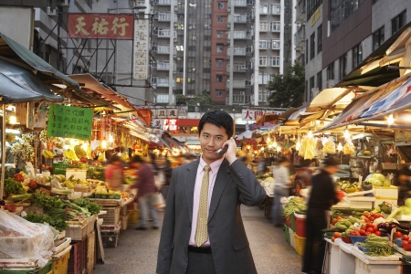 Young business man talking on mobile at street marketの写真素材