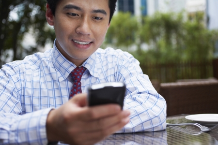 Business man text messaging sitting in outdoor cafe close upの写真素材
