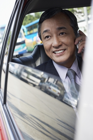 Businessman in a taxi talking on the phoneの写真素材