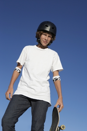 Teenage boy (16-17) holding skateboard outdoors portraitの写真素材