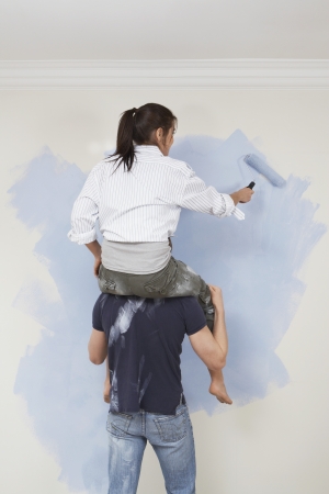 Woman riding shoulders of man to paint wallの写真素材