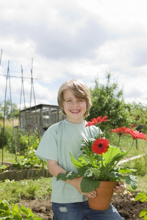 Boy holding flowers in gardenの写真素材