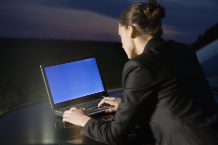 Business woman using laptop on carの写真素材