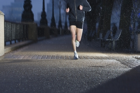Young man jogging on city pavement at dawn in Londonの写真素材