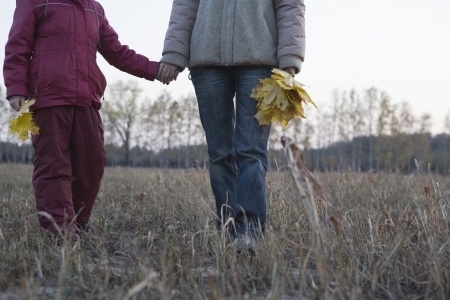 Mother and daughter holding hands in fieldの写真素材
