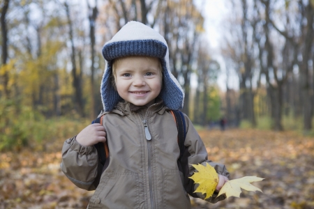 Boy holding leaves in park portraitの写真素材