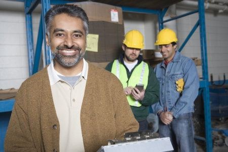 Cheerful men in factory colleagues in background
