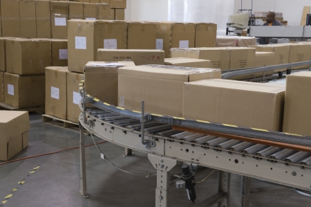 Cardboard boxes on conveyor belt in distribution warehouse