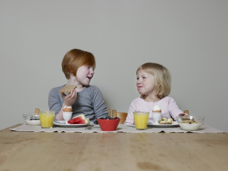 Sisters sit eating breakfast together and talkingの写真素材