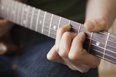 Young man playes chord on guitarの写真素材