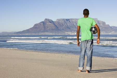 Rear view of man standing with football Table Mountain beachの写真素材