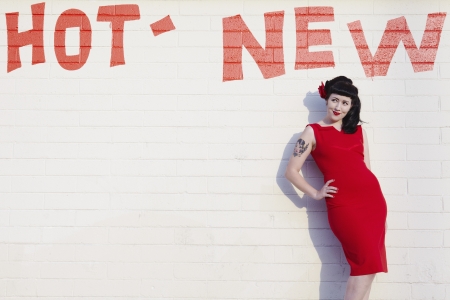 Retro woman in red dress posing against a brick wallの写真素材