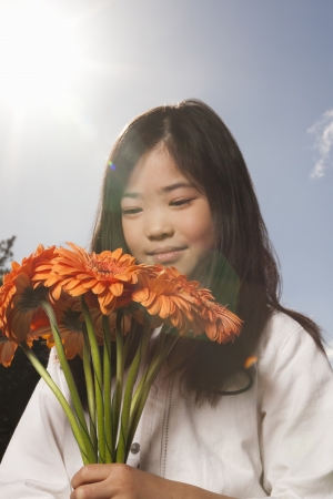 Asian girl holding bunch of flowersの写真素材