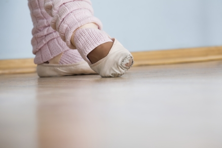 Young woman positions feet in ballet rehearsalの写真素材