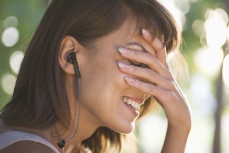 Woman covers her face laughing with headphones onの写真素材