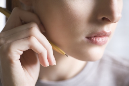Woman holds pencil next to faceの写真素材