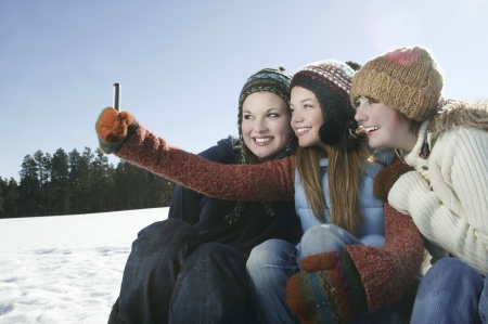Three girls take self portrait with camera phoneの写真素材
