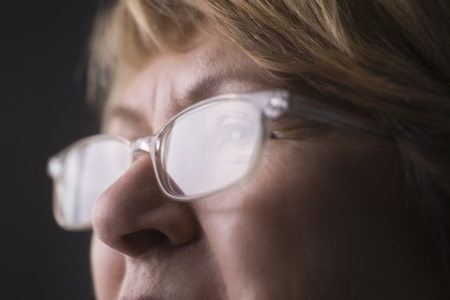 Mature woman with light reflecting on reading glassesの写真素材