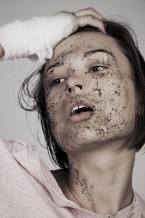 Young woman with bandage and muddy faceの写真素材