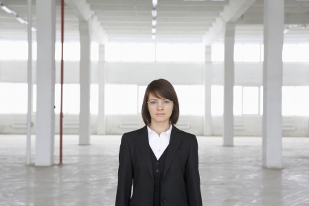 Business woman stands in empty warehouseの写真素材