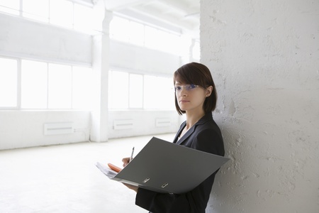 Business woman with file in empty warehouseの写真素材