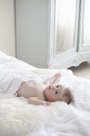 Baby boy lying on fur blanketの写真素材