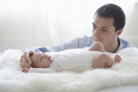 Father holds two week old newborn babies headの写真素材