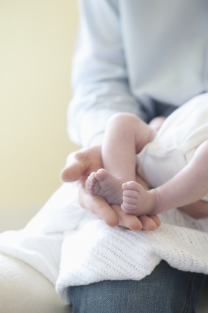 Father holding feet of two week old babyの写真素材