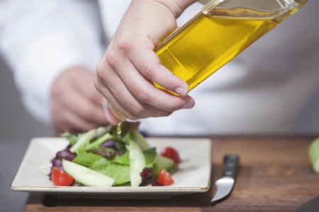 Mid- adult chef pours olive oil over side saladの写真素材