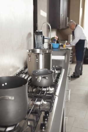 Chef works in kitchen with saucepans on hobの写真素材