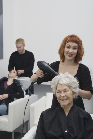 Stylist blow-drys elderly woman's hairの写真素材