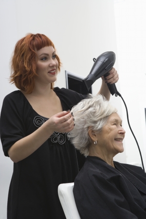 Stylist blow-drys elderly woman's hairの写真素材