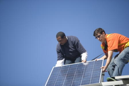 Two men lifting a large solar panelの写真素材