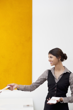 Young receptionist giving away templatesの写真素材