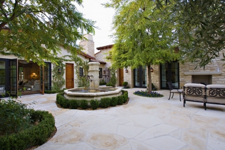 House exterior with a fountain  trees and patio furnitureの写真素材