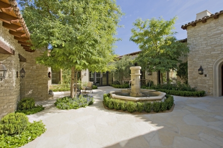 House exterior in daylight with a fountain  trees and plantsの写真素材