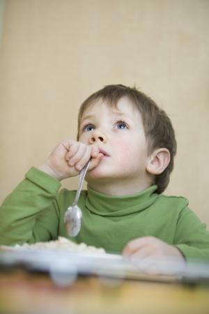Portrait young boy gazing upwards with spoon in his handの写真素材
