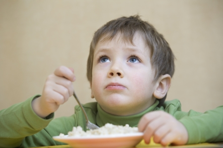 Portrait young boy gazing upwards  while eatingの写真素材