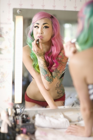 Mirror reflection of a young woman applying lipstickの写真素材