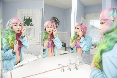Young woman applying makeup with multiple mirror reflectionsの写真素材